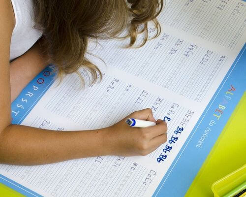 Dziewczyna uczy się alfabetu ze zmazywalną podkładką na biurko od ArtGlob.pl