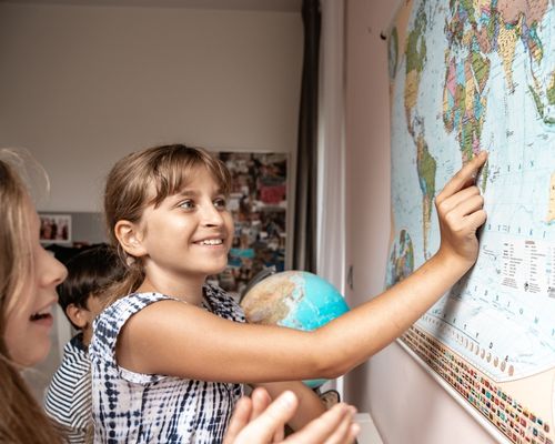 dziewczynka pokazuje Madagaskar na mapie świata ściennej