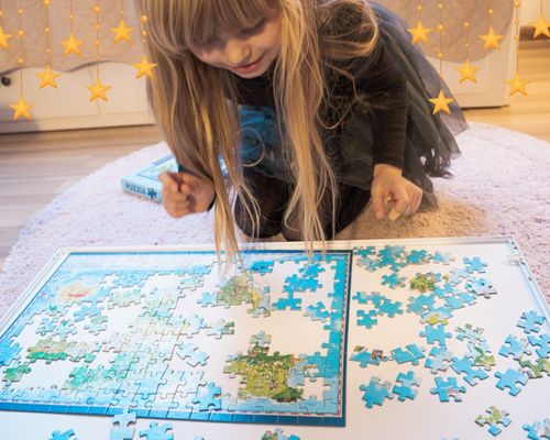 Dziewczynka układa puzzle z mapą świata dla dzieci